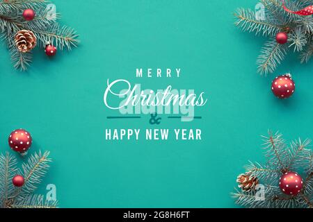 Christmas background. Text Merry Christmas on turquoise textile. Top view on fir twigs with Xmas red decorations, hearts, candy canes. Stock Photo