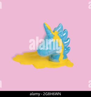 Creative idea made with blue painted unicorn head with yellow paint dripping on a pastel pink background. Minimal pop art fantasy concept. Copy space Stock Photo