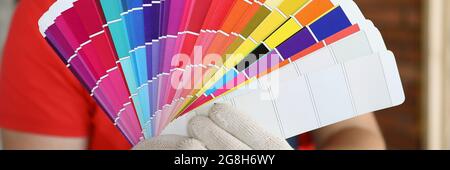 A man in gloves shows the color swatches in a crooked outline. A palette of colors for creating a design in an apartment Stock Photo