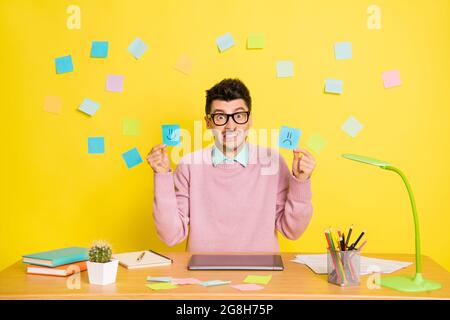 Photo of young unhappy upset worried sad man in glasses showing happy and sad paper emoji isolated on yellow color background Stock Photo