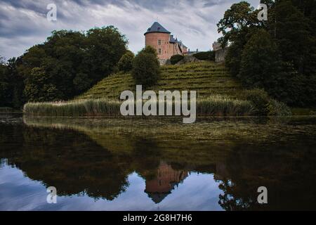 Gaasbeek Castle surrounded by greenery and a lake on a gloomy day in Lennik, Belgium Stock Photo