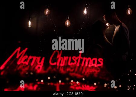 silhouette of a man and a woman on a background of lights in the dark, contour of the face, a kissing couple in the lights of the holiday, love and ro Stock Photo