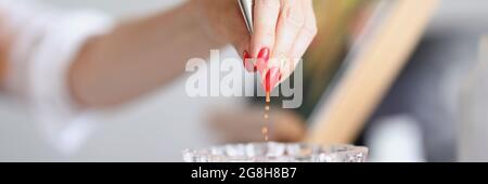 Hand pulls out a brush from a glass of water Stock Photo