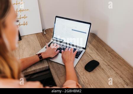 Close up of woman typing on laptop computer in home office Stock Photo
