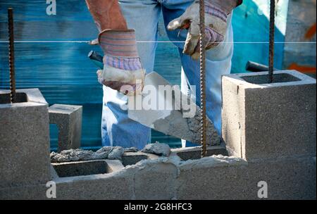 Construction site: building wall of concrete block. Mason is laying concrete blocks Stock Photo