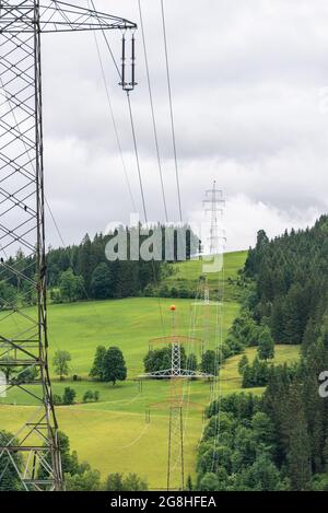 High voltage overhead power line, power pylon, steel lattice tower standing in the mountains landscape. Electricity distribution system in Europe Stock Photo