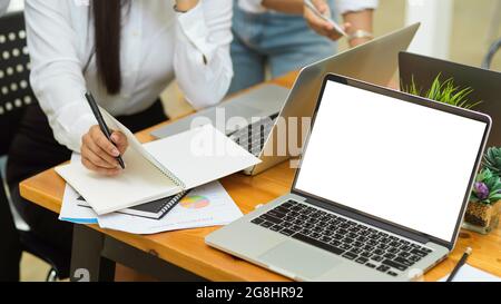 Cropped shot new employee sit and listen manager explain work scope while take note on planner with laptop in empty screen on the desk Stock Photo