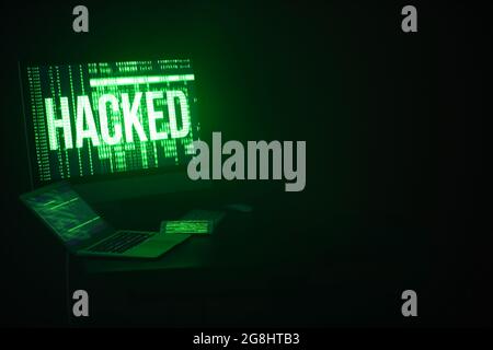 Computer with laptop and mobile phone at workplace of hacker in dark room Stock Photo