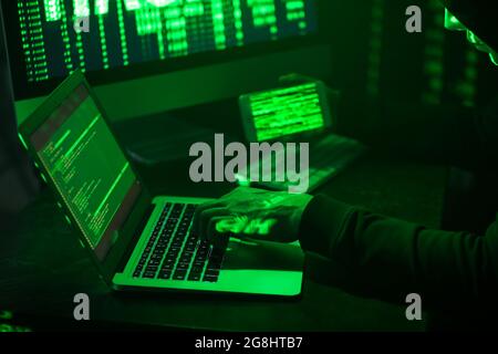 Hacker with mobile phone using computers in dark room Stock Photo