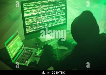 Hacker using computers in dark room Stock Photo