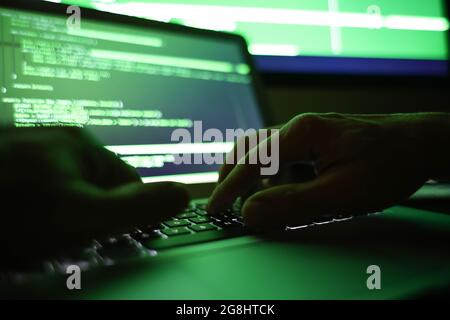 Hacker using computer in dark room, closeup Stock Photo