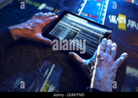 Hands of hacker with tablet computer on dark background Stock Photo