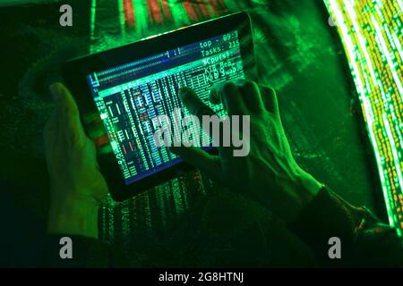 Hands of hacker with tablet computer on dark background Stock Photo