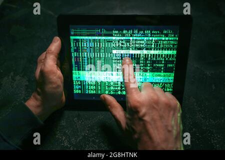 Hands of hacker with tablet computer on dark background Stock Photo