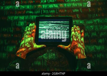 Hands of hacker with tablet computer on dark background Stock Photo