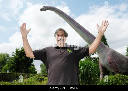 Leipzig, Germany. 20th July, 2021. Don Lessem, paleontologist and author, stands in front of a model of the Argentinosaurus at Leipzig Zoo. The life-size image is part of the exhibition 'The Gigantic Dino Adventure', which is on display there. Don Lessem also worked as a consultant for the film Jurassic Park. Credit: Sebastian Willnow/dpa-Zentralbild/dpa/Alamy Live News Stock Photo