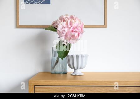 Vase with beautiful hydrangea flowers and decor on table near light wall Stock Photo