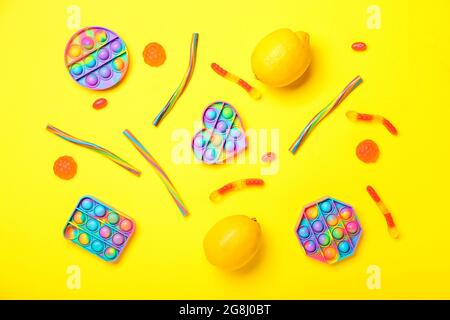 Pop it fidget toys, sweets and lemon on color background Stock Photo