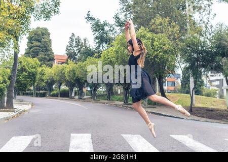 dancer jumping with arms up over a pedestrian crossing in the street Stock Photo