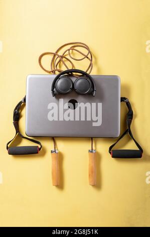 Sad fat man. Sports still life with a laptop. Laptop, jump rope and expander. Vertical frame. Stock Photo