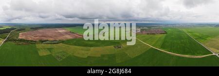 Aerial view of green agriculture field with rainy clouds in the sky. Nature landscape, bird eye view Stock Photo