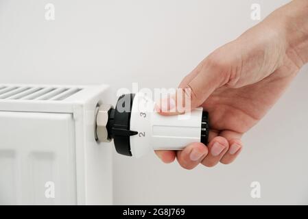 Heat radiator knob. Woman hand adjusting temperature on heating radiator Stock Photo