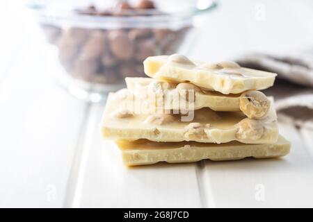 White chocolate bar with hazelnuts on white table. Stock Photo
