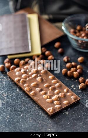 Chocolate bar with hazelnuts on black table. Stock Photo
