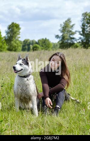 Owner girl playing with her siberian husky at field. Happy smiling woman with dog have a good time on weekend activity outdoors Stock Photo