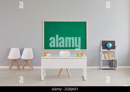 Modern school classroom interior with teacher's desk and chalkboard, space for design. Empty schoolroom with furniture Stock Photo