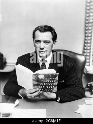 Producer PAUL GREGORY Portrait holding a copy of the book publicity for THE NIGHT OF THE HUNTER 1955 director CHARLES LAUGHTON novel Davis Grubb screenplay James Agate cinematographer Stanley Cortez music Walter Schumann art direction Hilyard M. Brown Paul Gregory Productions / United Artists Stock Photo