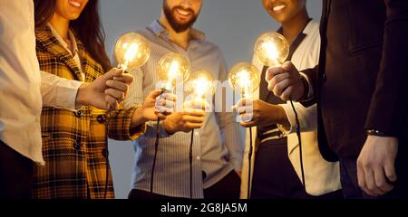 Happy business people holding light bulbs as metaphor for sharing ideas in creative community Stock Photo