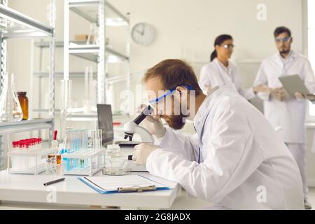 Professional male scientist looking through microscope in research laboratory Stock Photo