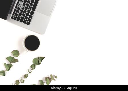 Frame made of laptop, mug of coffee and eucalyptus branches on a white background. Feminine workspace concept. Stock Photo
