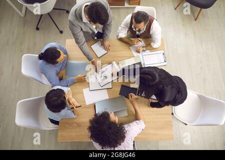 Top view of businesspeople working with laptops and and documents sitting at one desk. Stock Photo