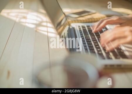 Hand woman fast typing on laptop on wooden desk. Stock Photo