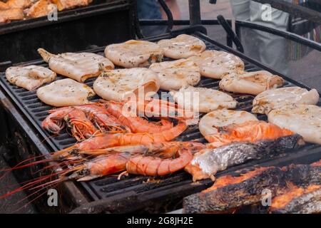 Process of cooking red langoustine shrimps, squids, salmon steaks on grill Stock Photo