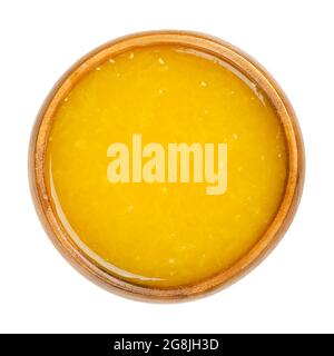 Freshly pressed orange juice with fruit pulp in a wooden bowl. Freshly squeezed orange-juice, a sweet refreshment with intense yellow color. Stock Photo