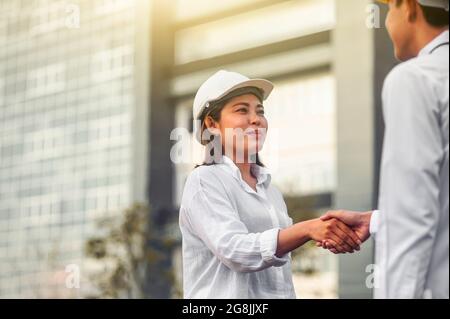 Hand Shake concept, Businesswoman shake hand and smile with Engineer outdoor on site work Stock Photo