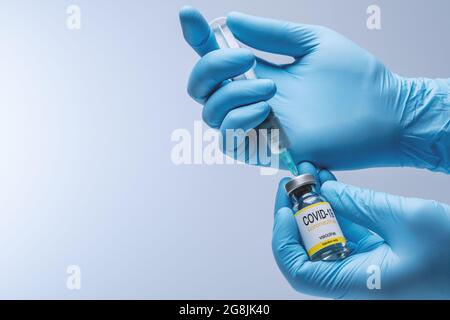 Hands in blue latex gloves with vaccine from glass vial. Healthcare And Medical concept. Stock Photo
