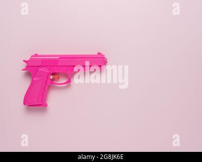 Pink handgun on pink pastel background. Minimal flat lay concept. Stock Photo