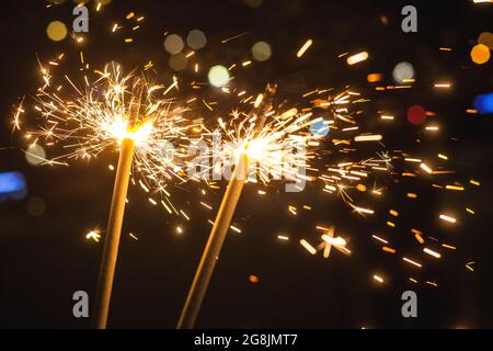 Bright glittering burning sparkler on blurred bokeh background Stock Photo