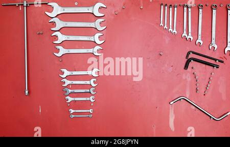 Various work tools hanging on a red stand at the car service workshop. Stock Photo