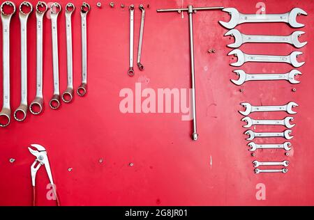 Various work tools hanging on a red stand at the car service workshop. Stock Photo