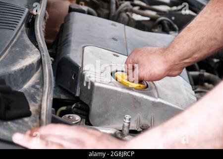 Hands of a mechanic repairman opening the car engine motor oil cap. Changing or checking car oil. Stock Photo