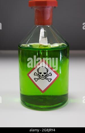 Toxic green chemical in a science laboratory. Glass flask with a skull and crossbones toxic haxard label Stock Photo