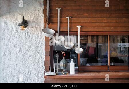Decorative vintage metal ladles hanging on the kitchen wall exterior Stock Photo