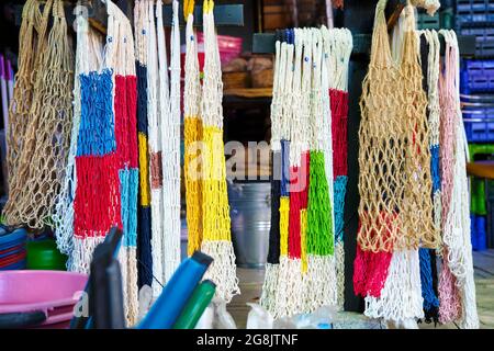 Colorful reusable cotton string mesh bags hanging and displayed at a shopping bag store. Stock Photo