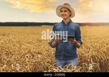 smart and modern farming. farm management. agricultural business. young woman successful farmer standing in cereal field with digital tablet in hands Stock Photo