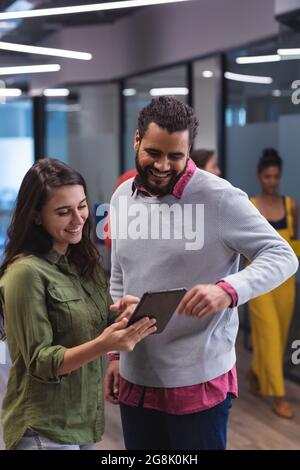 Two diverse creative colleagues using tablet and smiling Stock Photo